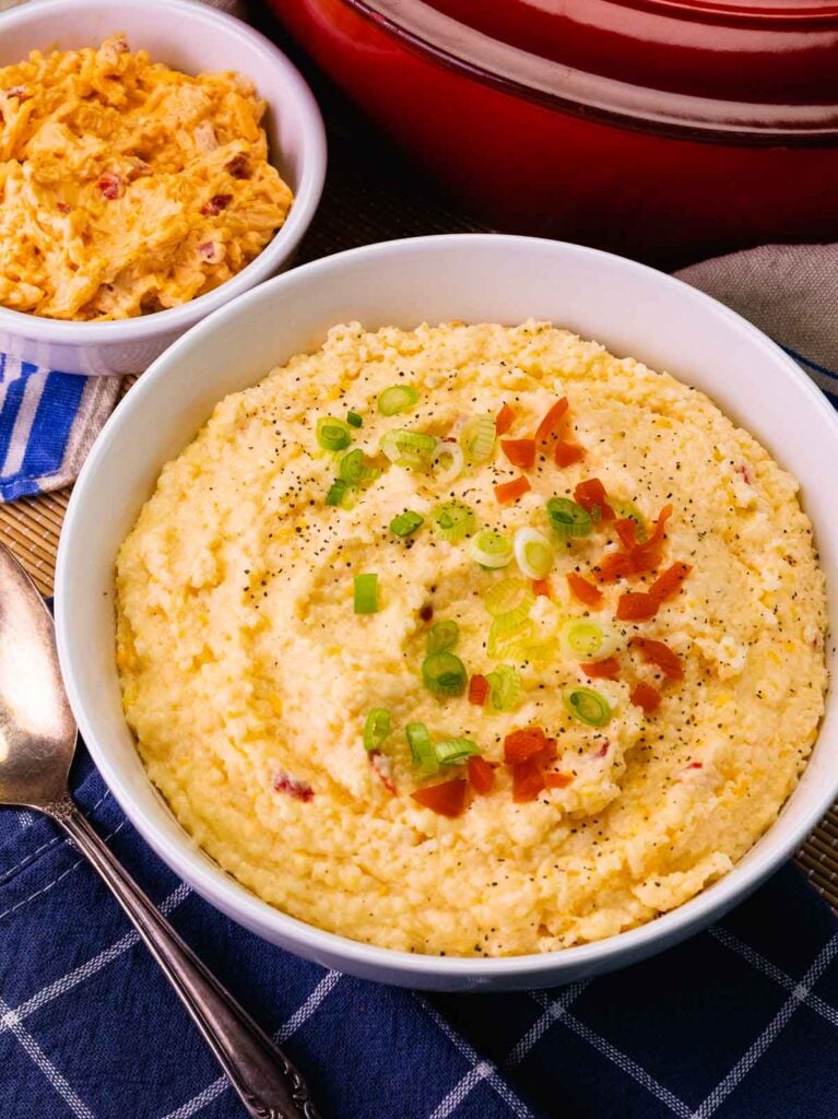 Big bowl of Pimento Cheese Grits topped with pimentos and sliced green onions.