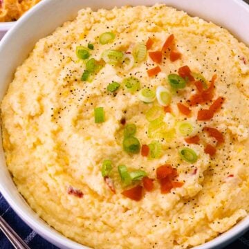Bowl of Pimento Cheese Grits topped with red pimento, pepper and slicked green onions.