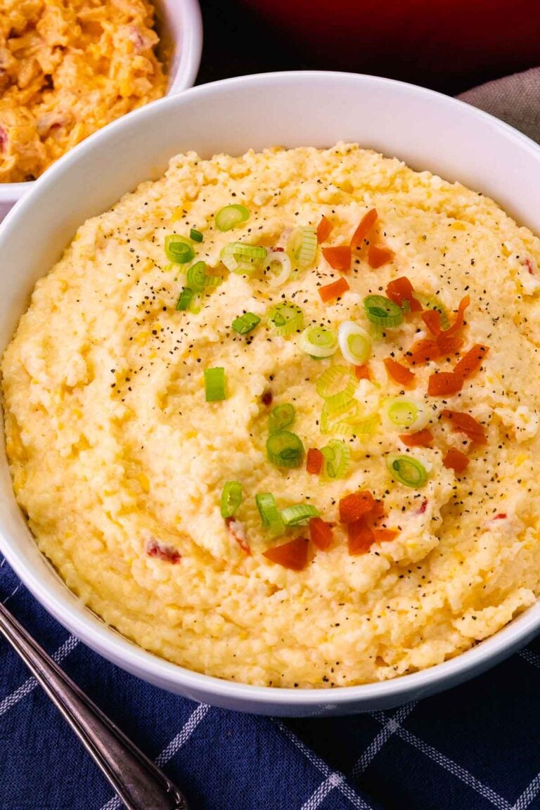 Bowl of Pimento Cheese Grits topped with red pimento, pepper and slicked green onions.