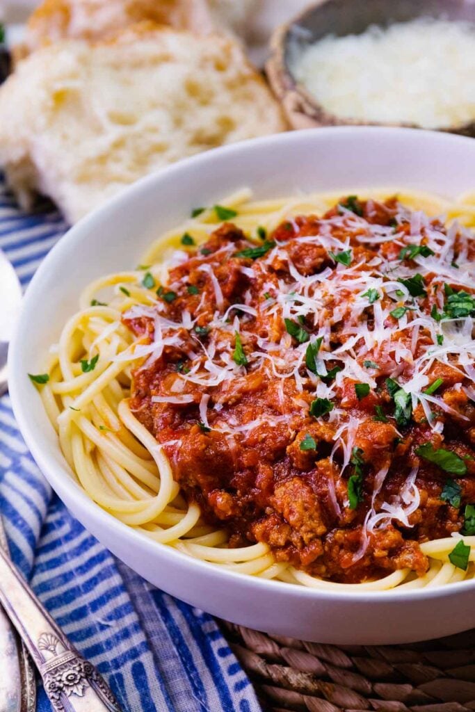Bowl of homemade spaghetti sauce topping noodles with cheese and parsley.