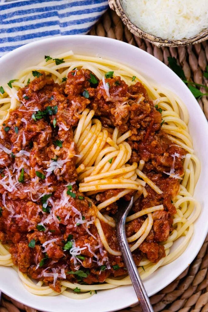 Bowl of spaghetti swirled on a fork with homemade meat sauce.