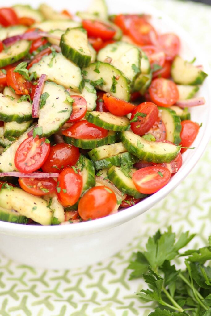 Tomato Cucumber Salad with homemade dressing in a white bowl.