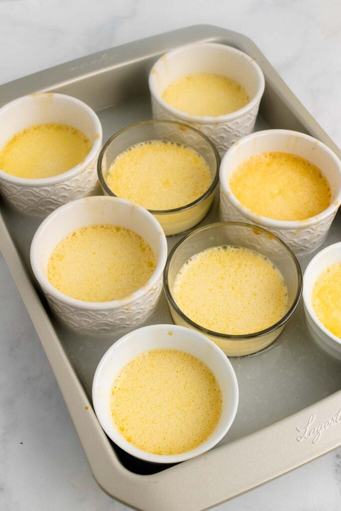 Lemon Creme Brulee in pots in a water bath for baking.