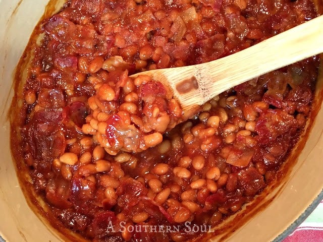 baked beans with bacon being cooked perfectly in a cast iron pot.