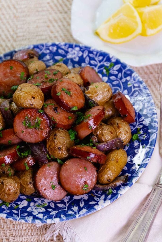 Beautiful blue plate loaded with Air Fryer Sausage And Potatoes sprinkled with parsley.