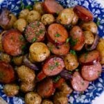 Beautiful blue plate loaded with Air Fryer Sausage And Potatoes sprinkled with parsley.