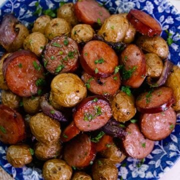 Beautiful blue plate loaded with Air Fryer Sausage And Potatoes sprinkled with parsley.