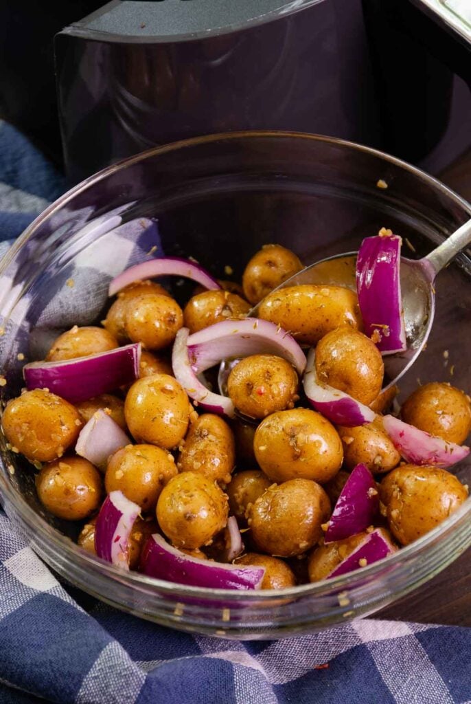 Baby potatoes and red onion tossed with olive oil, garlic and thyme to be cooked in the air fryer.