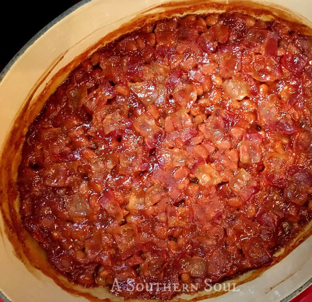 baked beans with bacon being cooked perfectly in a cast iron pot.