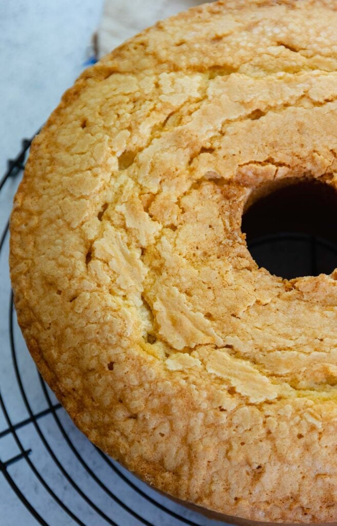 Million Dollar Pound Cake made with butter, sugar, flour, vanilla and almond extract cooking on a metal cake rack.