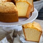 Slice of Million Dollar Pound Cake on a white plate along with sliced of cake served for dessert.
