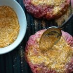 Homemade burger seasoning sprinkled on hamburger patties ready to cook.