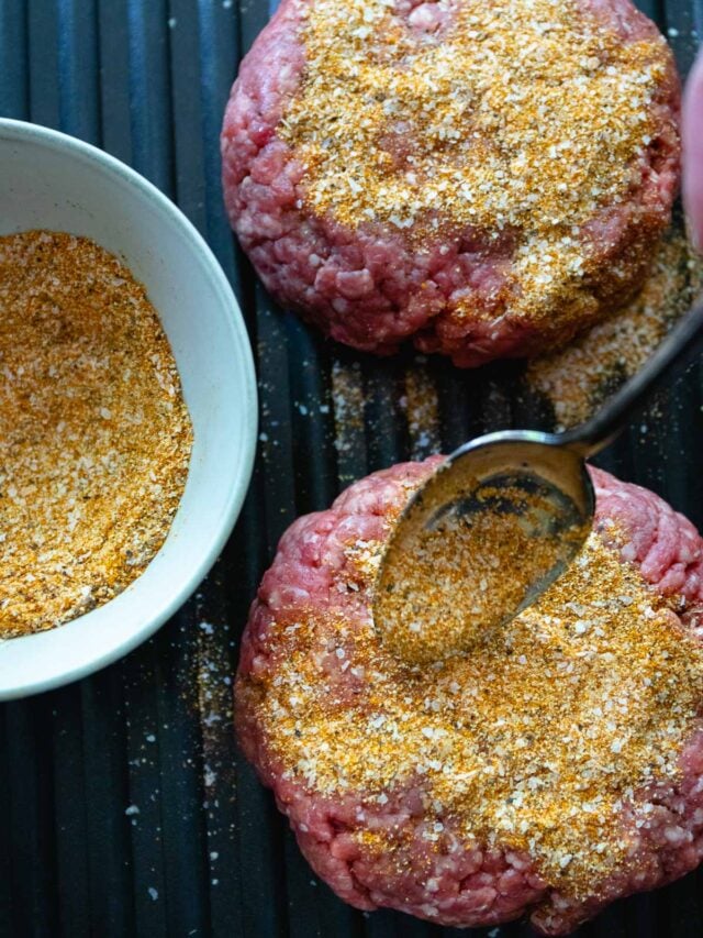 Homemade burger seasoning sprinkled on hamburger patties ready to cook.