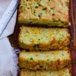 Loaf of delicious baked zucchini cheese bread, sliced on a cutting board served for dinner.
