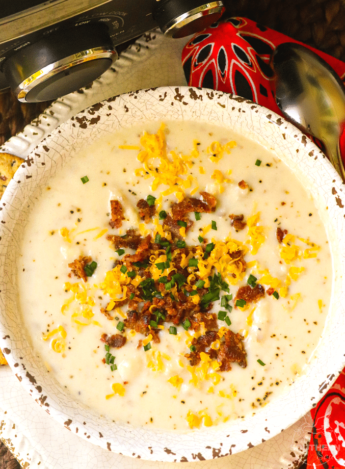 Creamy potato soup in white crackle bowl topped with crispy bacon, shredded cheddar, and green onions for Easy Slow Cooker Dinners for Busy