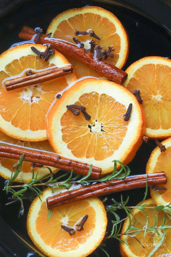 Orange slices with cinnamon sticks, cloves, and fresh rosemary arranged in black slow cooker for Easy Slow Cooker Dinners for Busy Weeknight