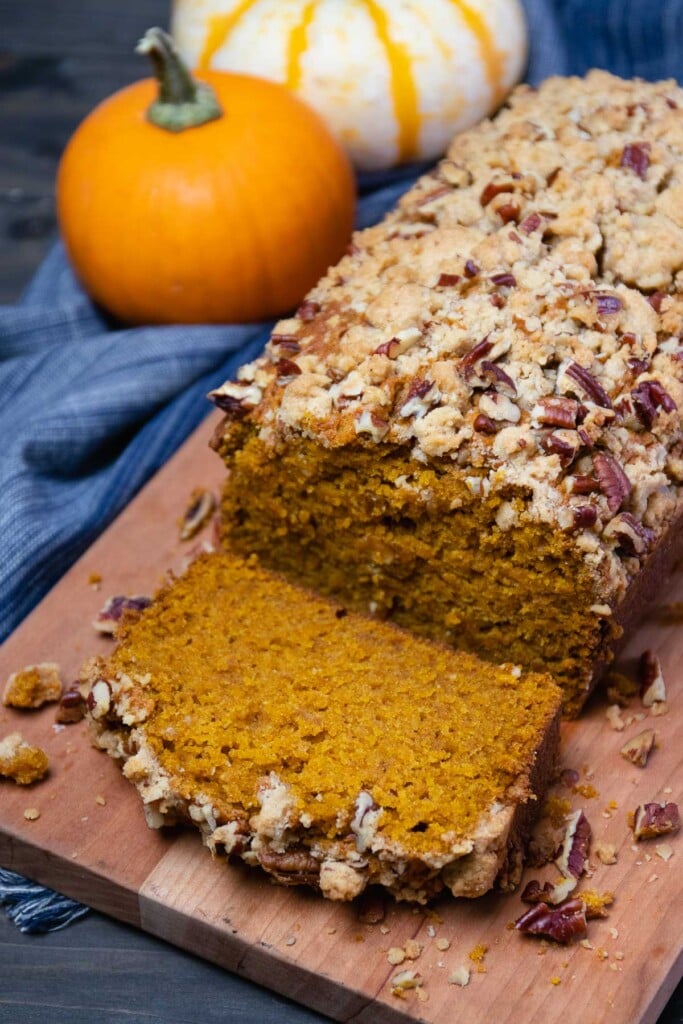 Pumpkin Bread topped with a pecan streusel sliced and served on a board is perfect for breakfast or a snack.