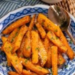 Air Fryer Roasted Carrots garnished with parsley and sea salt on a blue and white decorative plate, styled flat lay