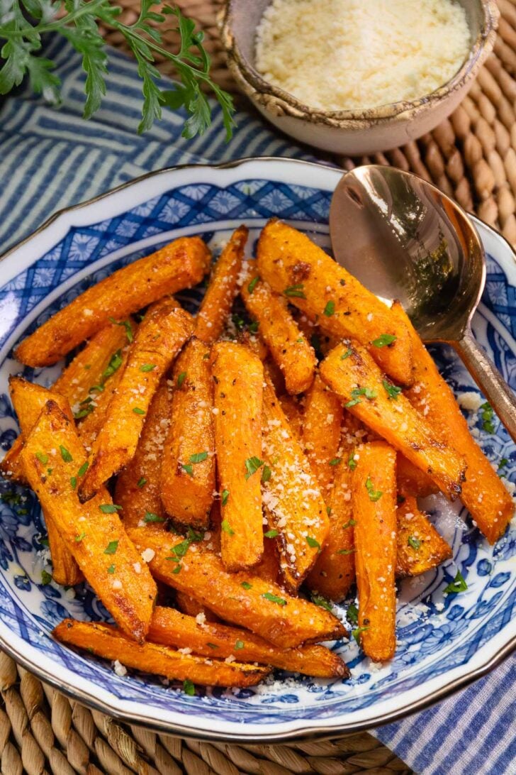 Air Fryer Roasted Carrots garnished with parsley and sea salt on a blue and white decorative plate, styled flat lay