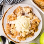 Grandma's Apple Crisp served warm in a white bowl with vanilla ice cream melting on top and cinnamon streusel crumble
