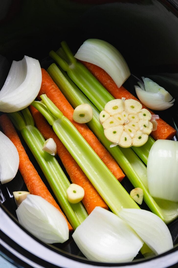 Carrots, celery, onions and garlic layered in the crock pot making a rack for turkey breast.