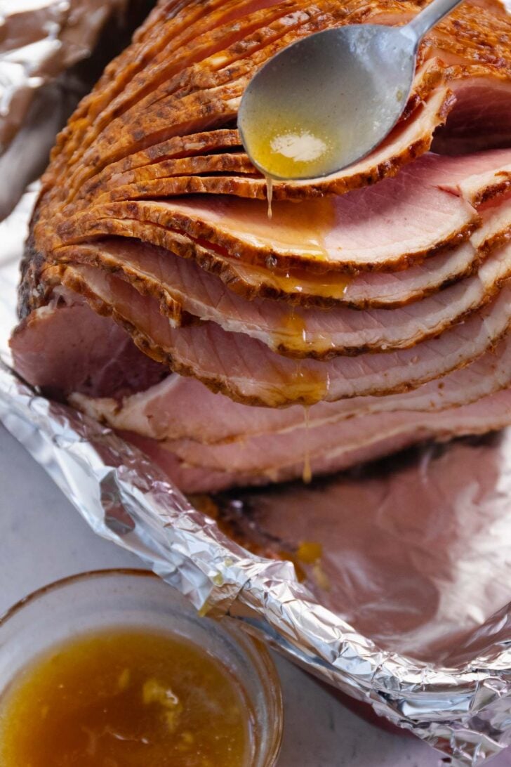 Honey and butter is spooned over a spiral sliced ham to make Copycat Honey Baked Ham recipe.