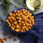 Pan Roasted Chickpeas (Crispy and Delicious) in blue bowl with white wine, fresh herbs, and navy napkin on gray surface