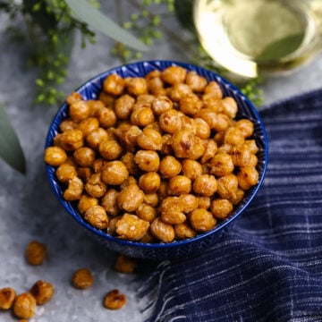 Pan Roasted Chickpeas (Crispy and Delicious) in blue bowl with white wine, fresh herbs, and navy napkin on gray surface