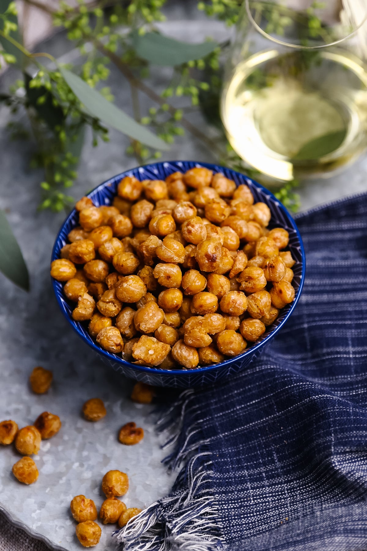 Pan Roasted Chickpeas (Crispy and Delicious) in blue bowl with white wine, fresh herbs, and navy napkin on gray surface