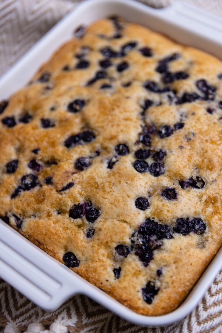 a slice of blueberry buttermilk cake with blueberries sprinkled in ready to eat.