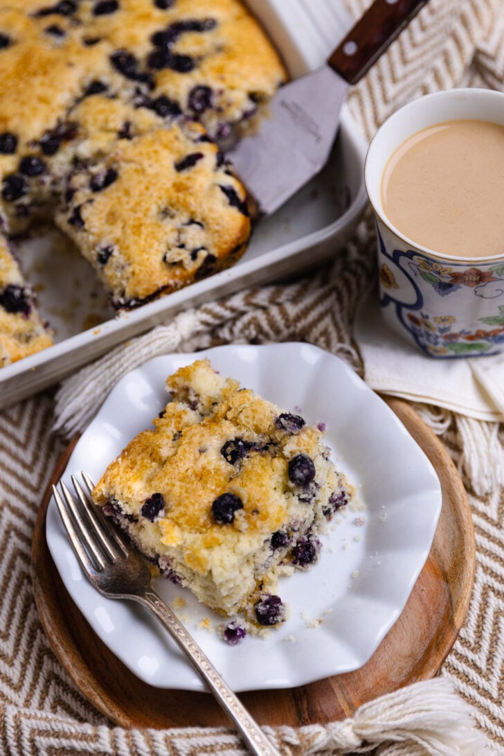 a slice of blueberry buttermilk cake with blueberries sprinkled in ready to eat.