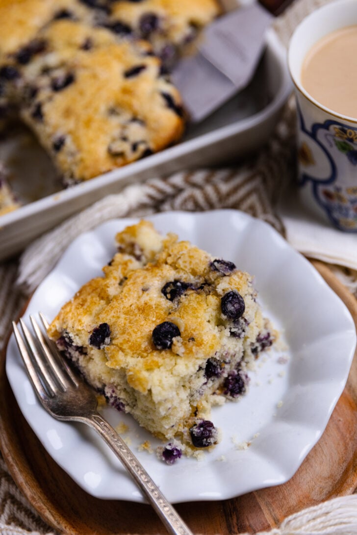 a slice of blueberry buttermilk cake with blueberries sprinkled in ready to eat.
