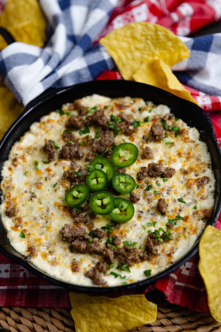 Tortilla chip dipped into Sausage Jalapeno Popper Dip baked in a cast iron skillet is creamy, meaty and spicy. It's a great hot appetizer to serve at family gatherings, parties, game day or anytime you are feeding a crowd.