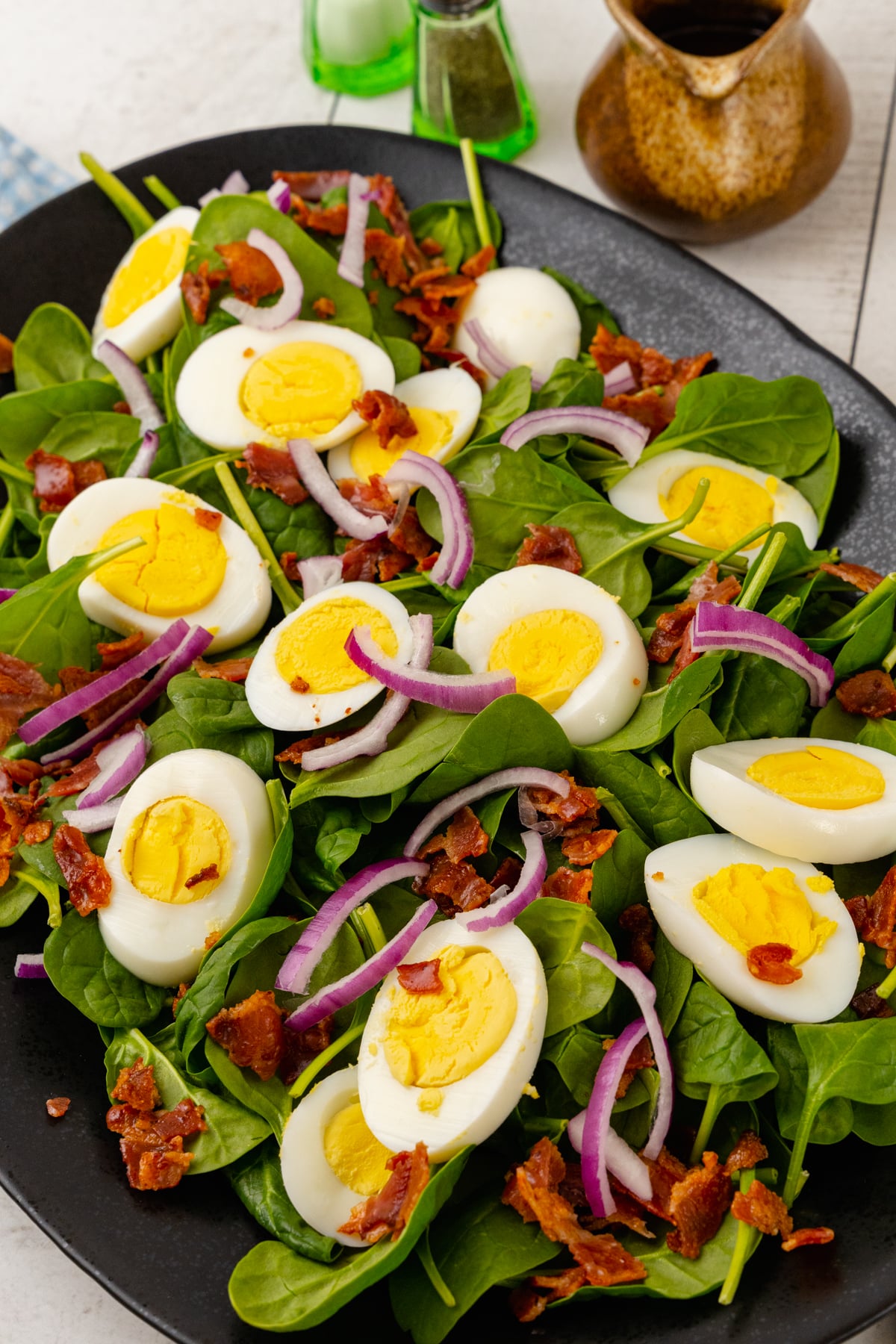 Fresh spinach, sliced red onion, crispy cooked bacon and boiled egg. Homemade salad dressing on the side with salt and pepper, along with bread for a light lunch or main dish.