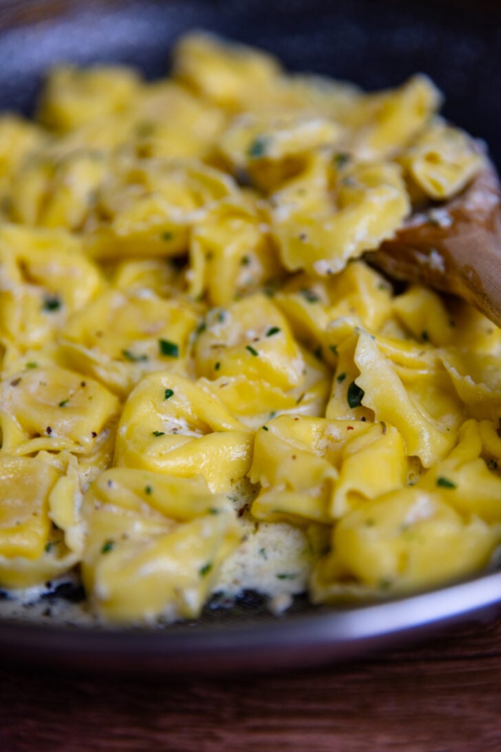 Cheese tortellini cooked in a cream sauce in a skillet on the stove top and serve as a side dish.
