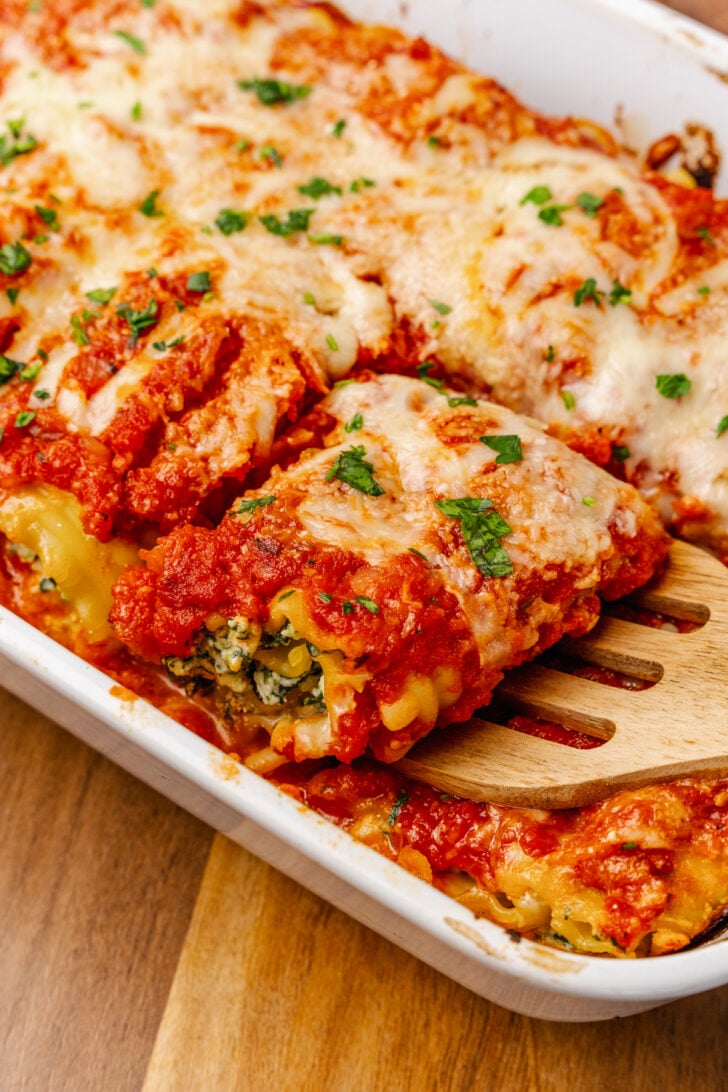Lasagna roll up stuffed with spinach and cheese baked in tomato sauce then topped with shredded cheese and fresh basil served for a weeknight meal.