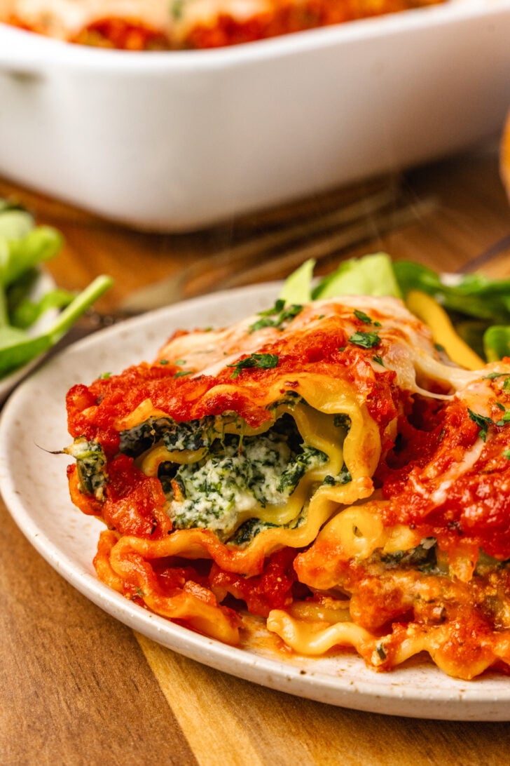Spinach and cheese roll ups topped with tomato sauce and baked with a cheese topping is a twist on traditional lasagna that is so easy to make for a family meal.