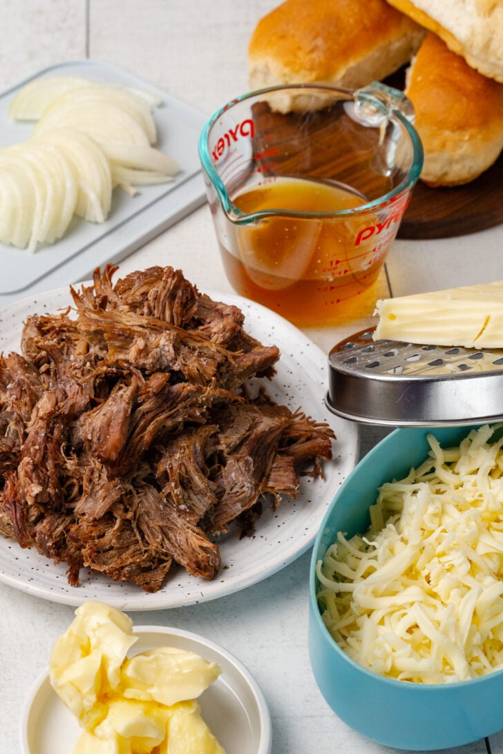 Cooked leftover roast beef, onions, butter, grated cheese and hoagie rolls for Roast Beef and Cheese Sandwiches.