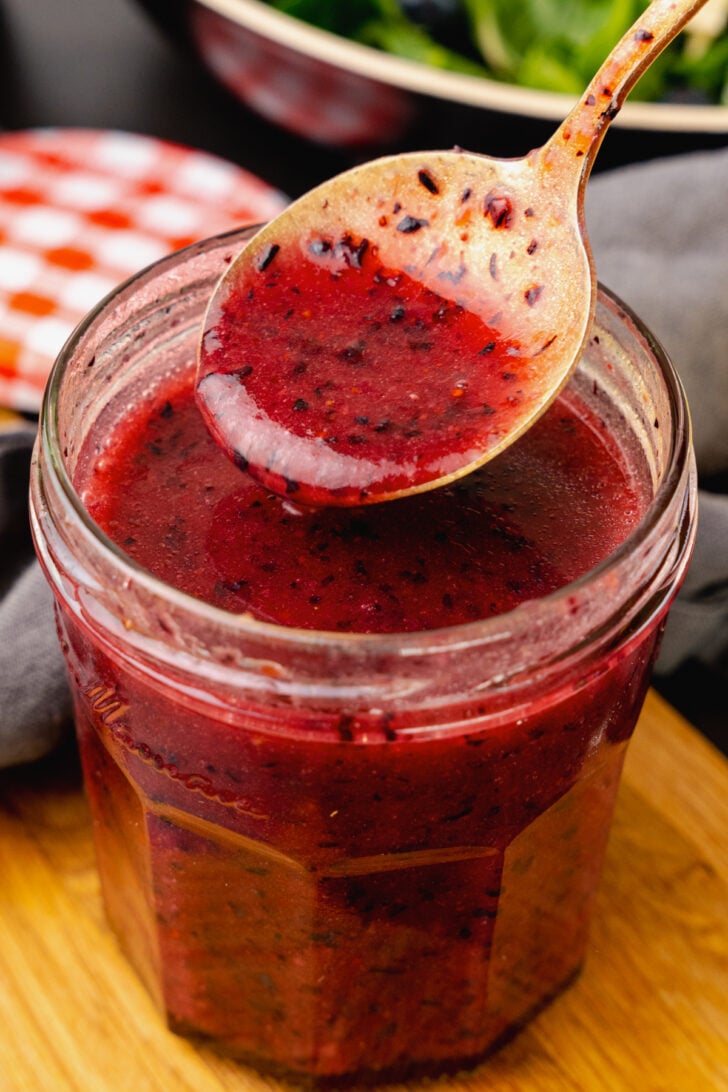 Spoonful of homemade blueberry vinaigrette salad dressing with lemon, olive oil and fresh crushed blueberries.