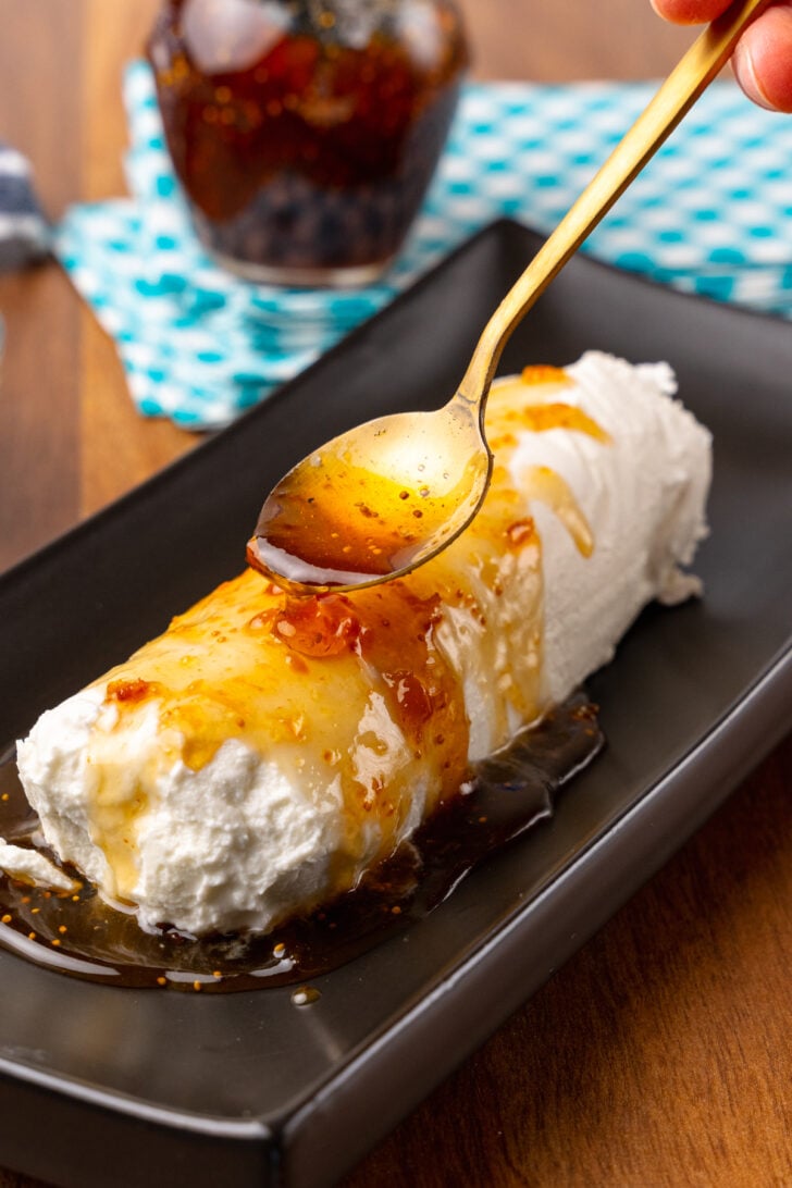 Log of goat cheese smothered with a spoonful of honey and fig jam.