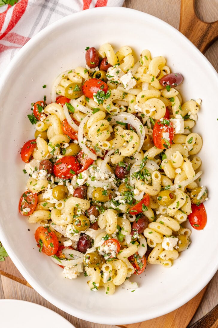 Greek pasta salad made with a store-bought shortcut is easy to make with pasta, feta cheese, tomatoes and onions in a light olive oil dressing. It's the perfect side dish or main to serve any time of the year!