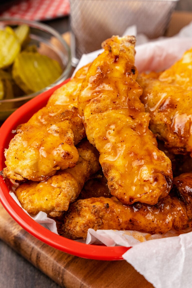 Red basket with Nashville Hot Chicken Tenders cooked in the air fyer area crispy and spicy served with pickles.