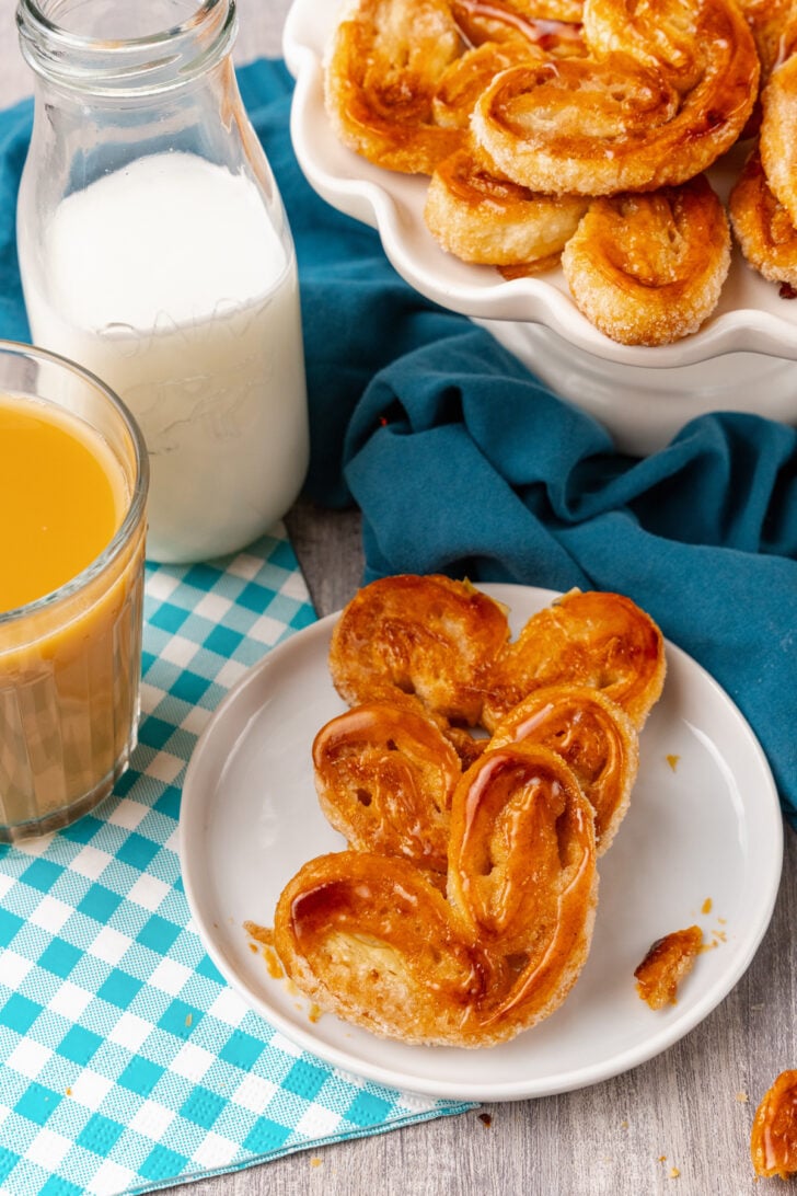 Classic Palmiers with a dash of cinnamon baked until golden brown served on a white plate with a latte and milk.