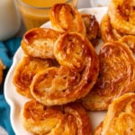 Classic Palmiers with a dashed of cinnamon baked until golden brown served on a white plate with a latte.