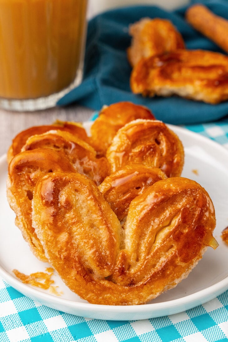 Classic Palmiers with a dashed of cinnamon baked until golden brown served on a white plate with a latte.