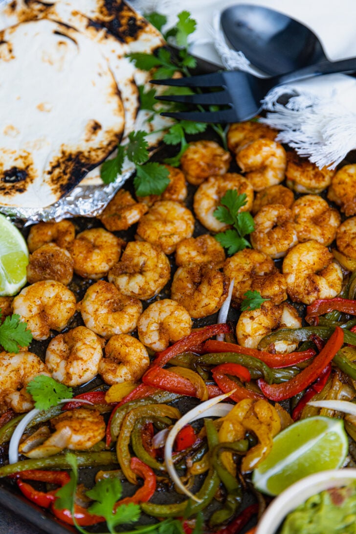 Flour tortillas, lime wedges, guacamole served with Sheet Pan Chili Lime Shrimp Fajitas.