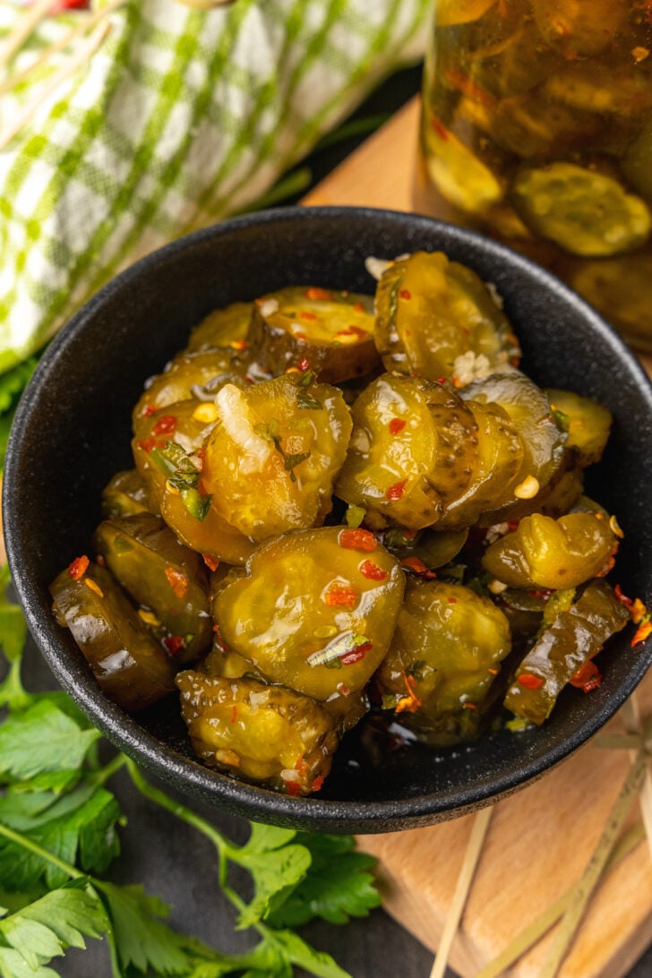 Black bowl with Sweet Heat Pickles marinated in red pepper, sugar, garlic, parsley and jalapeños are crazy delicious and so easy to make. They are great as a snack, with burgers, chicken, and perfect for a charcuterie board!