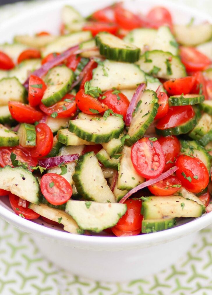 Tomato Cucumber Salad with homemade dressing in a white bowl.