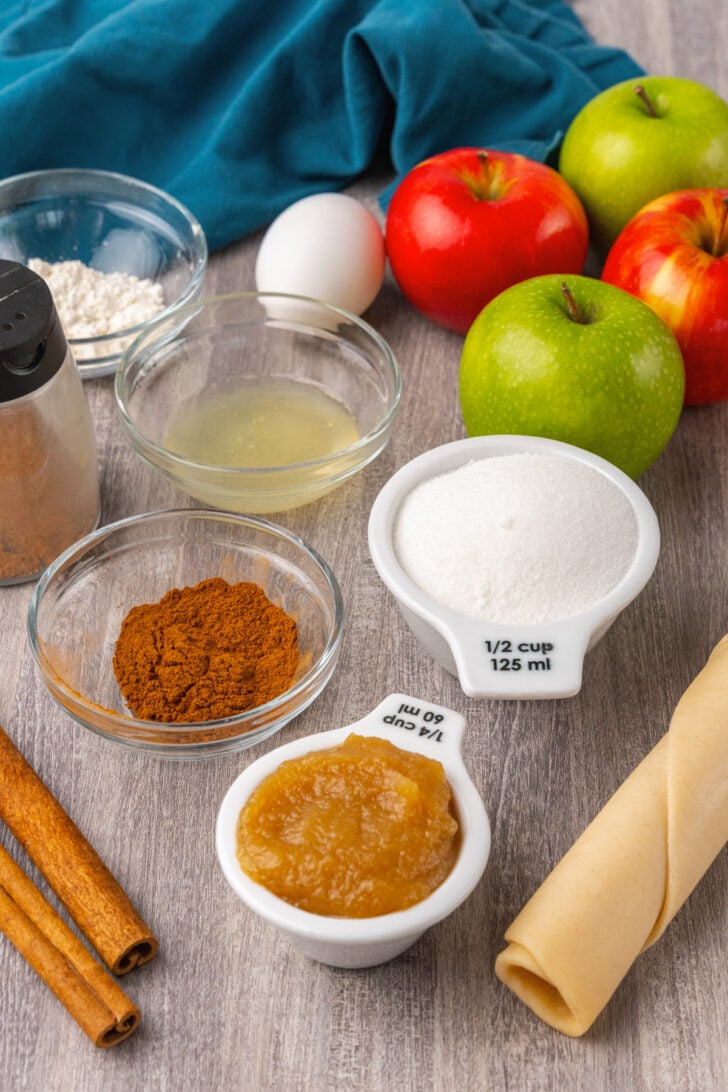 Apple, pie dough, apple butter, sugar, cinnamon and other ingredients gathered for apple crostata recipe.