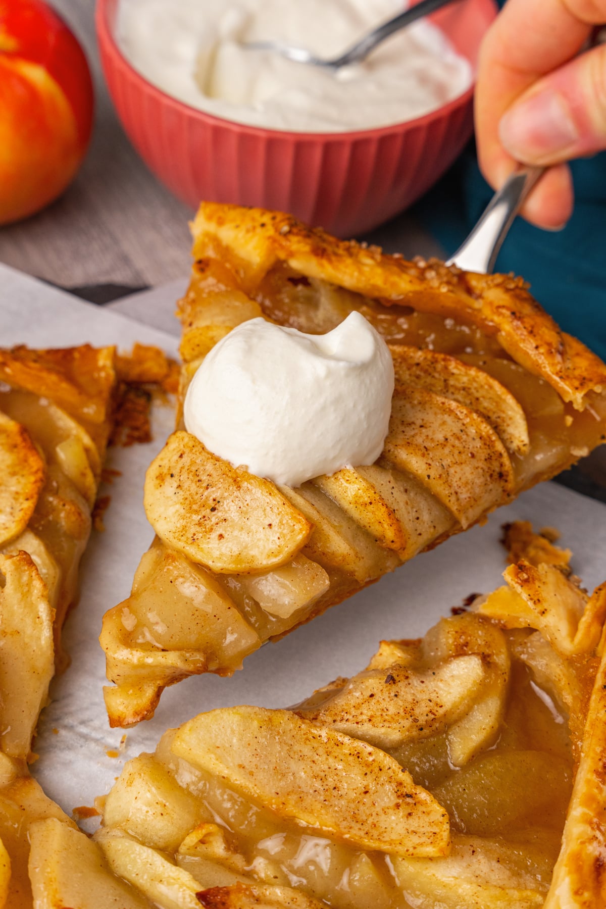 Sliced Apple Crostata sliced and being served with a pie server and homemade whipped cream.